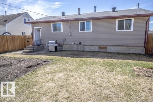 Rear exterior featuring beige horizontal siding, white-framed windows, and a brown asphalt shingle roof - 4822 45 Ave, St. Paul Town, AB - Outdoor With Exterior