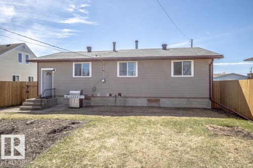 Rear exterior featuring neutral siding, a grey shingle roof, and white window trim - 4822 45 Ave, St. Paul Town, AB - Outdoor With Exterior