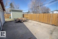 Concrete patio area featuring a detached storage shed with light green siding and a private wood fence - 