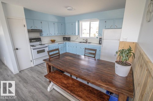 Kitchen with light blue cabinetry, light countertops, and wood-finish flooring - 4822 45 Ave, St. Paul Town, AB - Indoor Photo Showing Kitchen With Double Sink