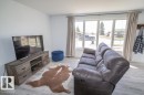 Living area featuring light wood-finish flooring, a wood-look media console with dark hardware, and a large window with white framing - 4822 45 Ave, St. Paul Town, AB  - Indoor Photo Showing Living Room 