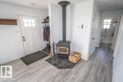 Entryway featuring wood-finish flooring, a black wood-burning stove with a tile hearth, and a white paneled door with glass inserts - 