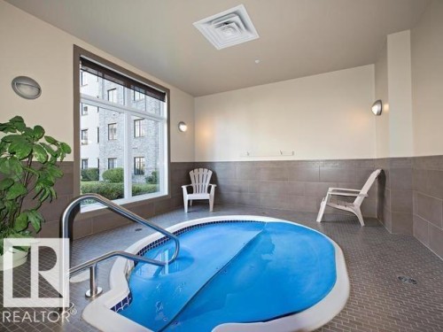 Indoor spa with a blue cover, featuring a stainless steel handrail - 109 160 Magrath Rd, Edmonton, AB 