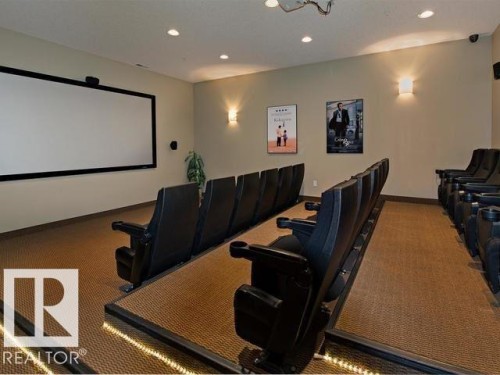Dedicated theater room featuring a large projection screen and tiered seating - 109 160 Magrath Rd, Edmonton, AB 