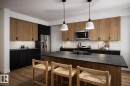 Kitchen featuring a wood-finish island with a dark countertop and integrated sink, stainless steel appliances, two-tone cabinetry, and wood-finish flooring - 18 Brickyard View, Stony Plain, AB  - Indoor Photo Showing Kitchen 