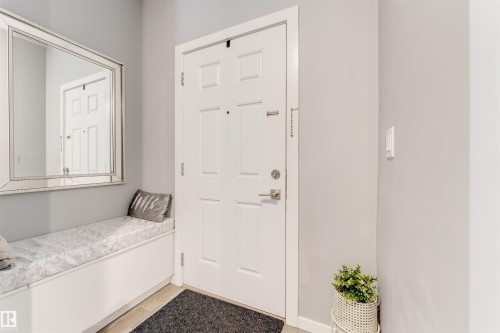 Entryway featuring a paneled door with brushed nickel hardware, light gray walls, built-in bench seating with a cushion, and a large framed mirror - 2652 Maple Way, Edmonton, AB - Indoor Photo Showing Other Room