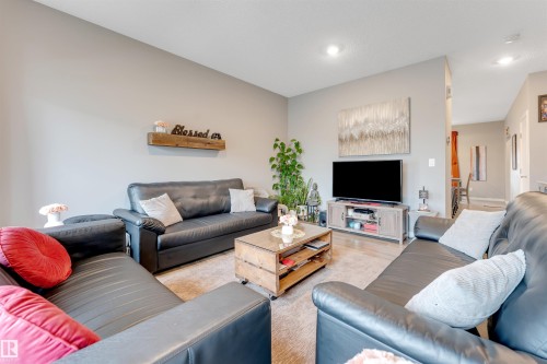 Spacious living area featuring light gray walls, recessed lighting, wood-finish flooring, and a plush area rug - 2652 Maple Way, Edmonton, AB - Indoor Photo Showing Living Room