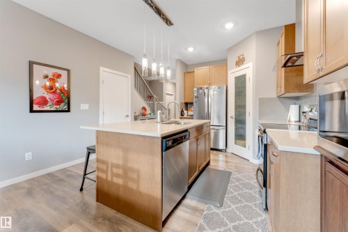 Kitchen island with a light-toned countertop and integrated stainless steel dishwasher - 2652 Maple Way, Edmonton, AB - Indoor Photo Showing Kitchen