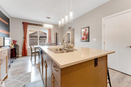 Kitchen island featuring a double basin stainless steel sink, a gooseneck faucet, and light-toned countertops - 2652 Maple Way, Edmonton, AB - Indoor Photo Showing Kitchen With Double Sink