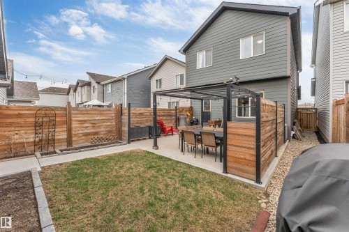 Private backyard featuring a concrete patio with a built-in pergola, horizontal wood fencing, a grass lawn, and a side yard with gravel - 2652 Maple Way, Edmonton, AB - Outdoor With Deck Patio Veranda With Exterior