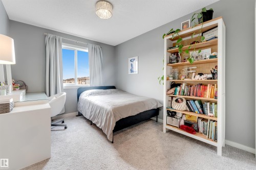 Carpeted room featuring a window with white trim, a built-in light fixture, and a tall built-in bookshelf with light wood-finish shelving - 2652 Maple Way, Edmonton, AB - Indoor Photo Showing Bedroom