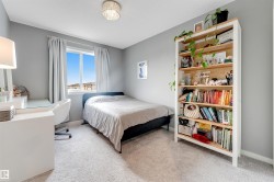 Carpeted room featuring a window with white trim, a built-in light fixture, and a tall built-in bookshelf with light wood-finish shelving - 