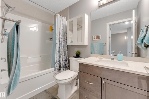 Full bathroom featuring a single vanity with integrated sink, stone countertop, and wood-finish cabinetry - 2652 Maple Way, Edmonton, AB - Indoor Photo Showing Bathroom