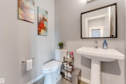 Bathroom featuring a white pedestal sink with chrome faucet, framed mirror, and toilet - 