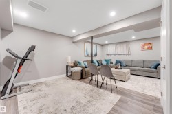 Spacious lower-level area with light-toned walls and wood-finish flooring - 