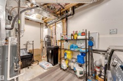 Utility space featuring exposed ductwork, a water heater, and a water treatment system - 