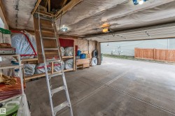 Attached garage with exposed wood beam ceiling, concrete flooring, and an overhead door - 