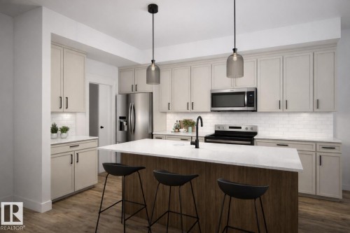 Modern kitchen featuring a central island with a light-toned countertop, a matte black faucet, and stainless steel appliances - 22 Brickyard View, Stony Plain, AB - Indoor Photo Showing Kitchen With Upgraded Kitchen
