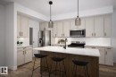 Modern kitchen featuring a central island with a light-toned countertop, a matte black faucet, and stainless steel appliances - 22 Brickyard View, Stony Plain, AB  - Indoor Photo Showing Kitchen With Upgraded Kitchen 