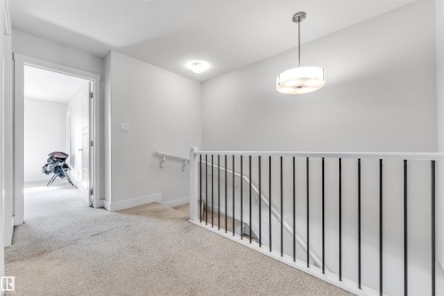 Upper-level hallway with neutral carpet, white walls, modern pendant lighting, and a contemporary baluster railing - 1536 21 Street, Edmonton, AB - Indoor Photo Showing Other Room