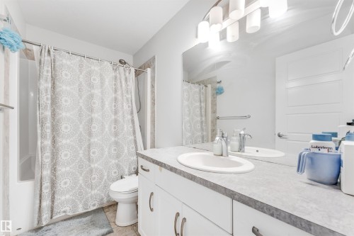 Bathroom featuring a white vanity with an integrated sink, a large mirror, and a tub/shower combination with partial tile surround - 1536 21 Street, Edmonton, AB - Indoor Photo Showing Bathroom