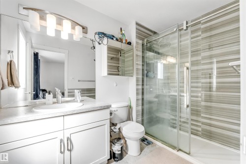 Bathroom featuring a spacious walk-in shower with horizontal striped tiling and a sliding glass door - 1536 21 Street, Edmonton, AB - Indoor Photo Showing Bathroom