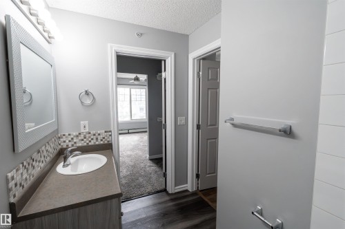 Bathroom vanity with an integrated sink, mosaic tile backsplash, and a framed mirror with overhead lighting - 4407 23 Street, Edmonton, AB - Indoor Photo Showing Bathroom