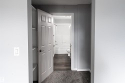 Bathroom featuring a white tub, toilet, and wood-finish flooring - 