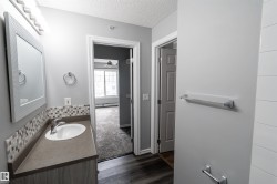 Bathroom vanity with an integrated sink, mosaic tile backsplash, and a framed mirror with overhead lighting - 