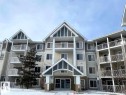 Multi-story residential building featuring balconies with white railings, a prominent gabled main entrance, varied siding textures, and multiple windows across its facade - 4407 23 Street, Edmonton, AB  - Outdoor With Facade 