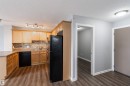 Open-concept kitchen with wood-finish flooring, light wood cabinetry, stone-finish countertops, black appliances, and a textured tile backsplash - 4407 23 Street, Edmonton, AB  - Indoor Photo Showing Kitchen 