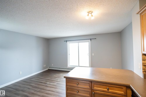 Kitchen island with wood-finish cabinetry and a solid surface countertop, offering functional counter space - 4407 23 Street, Edmonton, AB - Indoor