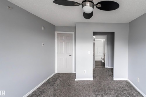 Carpeted room with light gray walls, a ceiling fan with integrated lighting, and a white paneled door - 4407 23 Street, Edmonton, AB - Indoor Photo Showing Other Room