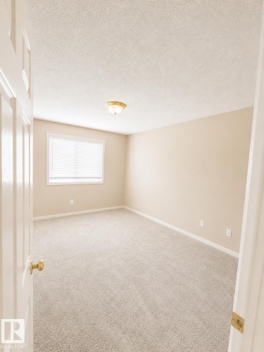 Carpeted room featuring a single window with blinds, a ceiling-mounted light fixture, and neutral-toned walls - 704 83 Street, Edmonton, AB - Indoor Photo Showing Other Room