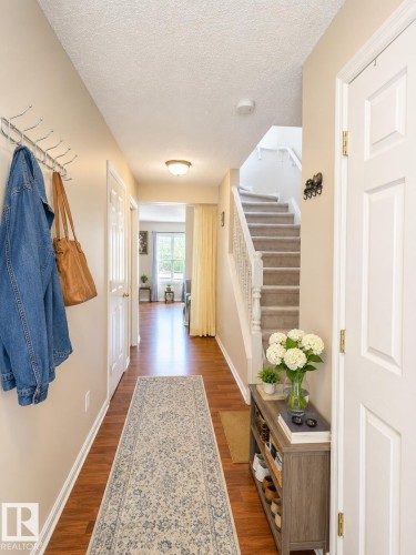 Entryway featuring wood-finish flooring, a carpeted staircase with white railing, and flush-mount lighting - 704 83 Street, Edmonton, AB - Indoor Photo Showing Other Room