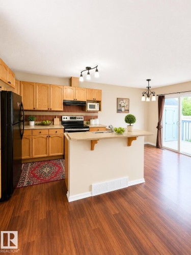Kitchen featuring wood-finish flooring, light wood cabinetry, a four-burner electric range, an over-the-range microwave, and a black refrigerator - 704 83 Street, Edmonton, AB - Indoor Photo Showing Kitchen