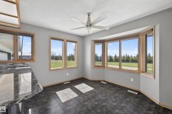 Bay window with natural wood trim, contemporary ceiling fan, dark tile flooring, and light gray walls - 