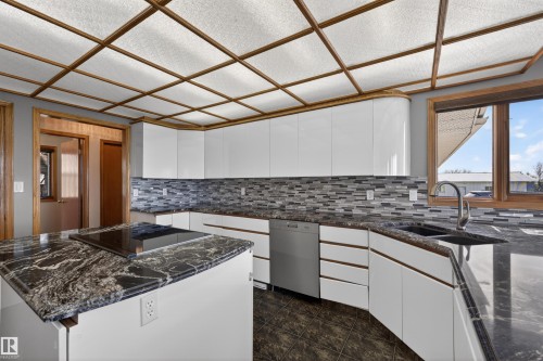 Modern kitchen featuring high-gloss white cabinetry, dark stone countertops, and a mosaic tile backsplash - 19403 Fort Road, Edmonton, AB - Indoor Photo Showing Kitchen With Double Sink With Upgraded Kitchen