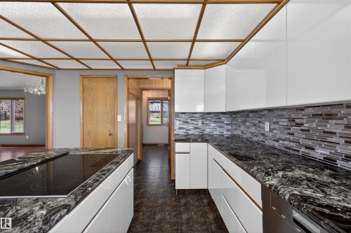 Kitchen featuring white cabinetry, dark speckled countertops, a tile backsplash, and a built-in cooktop - 19403 Fort Road, Edmonton, AB - Indoor Photo Showing Kitchen With Upgraded Kitchen