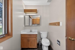 Bathroom featuring a wood-framed window, vanity with integrated sink, wall-mounted medicine cabinet, and a white toilet - 