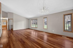 Spacious room featuring wood-finish flooring, vaulted ceilings, and a decorative chandelier - 