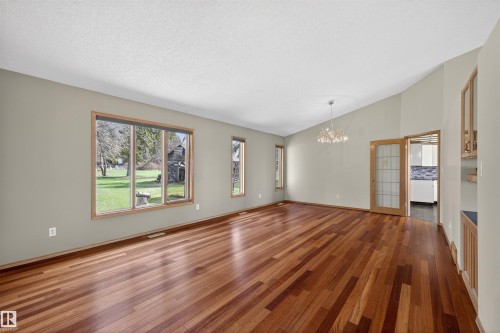 Spacious interior featuring wood-finish flooring, multiple windows, a decorative chandelier, and vaulted ceilings - 19403 Fort Road, Edmonton, AB - Indoor Photo Showing Other Room