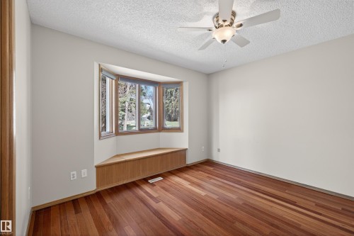 Bay window with a built-in window seat, wood-finish flooring, textured ceiling, and a ceiling fan with integrated lighting - 19403 Fort Road, Edmonton, AB - Indoor Photo Showing Other Room