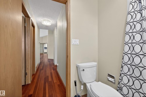 Hardwood-style flooring extends through the hallway, complemented by light-toned wall paint - 19403 Fort Road, Edmonton, AB - Indoor Photo Showing Bathroom