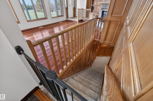 Staircase featuring wood paneling, wood-finish railings, and carpeted treads - 19403 Fort Road, Edmonton, AB - Indoor Photo Showing Other Room