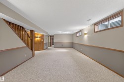 Expansive carpeted room featuring a wooden staircase and paneling - 