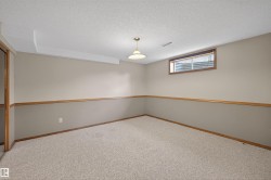 Carpeted room featuring two-tone wall paint with wood trim, a window with wood trim, and a ceiling-mounted light fixture - 