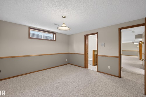 Carpeted room with a drop ceiling, wood-trimmed paneling, and a single-pane window - 19403 Fort Road, Edmonton, AB - Indoor Photo Showing Other Room