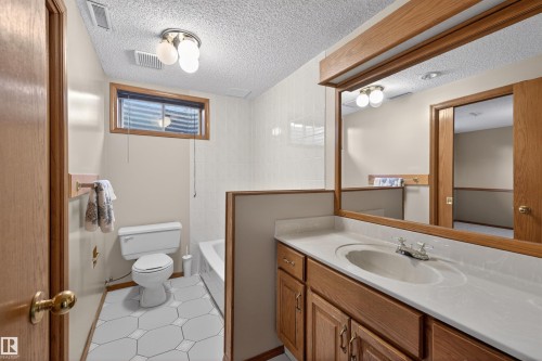 Bathroom featuring a single vanity with a white countertop and integrated sink, wood-finish cabinetry, a framed wall mirror, and hexagonal floor tiling - 19403 Fort Road, Edmonton, AB - Indoor Photo Showing Bathroom