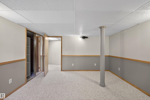 Spacious room featuring light-colored carpet flooring, two-tone painted walls with wood trim, and a drop ceiling - 19403 Fort Road, Edmonton, AB - Indoor Photo Showing Other Room